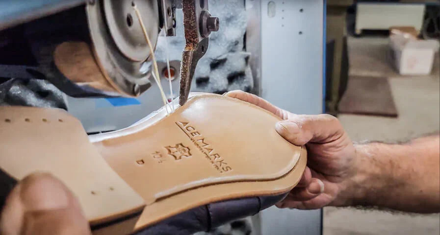Shoemaker stitching a leather shoe sole in an Ace Marks workshop