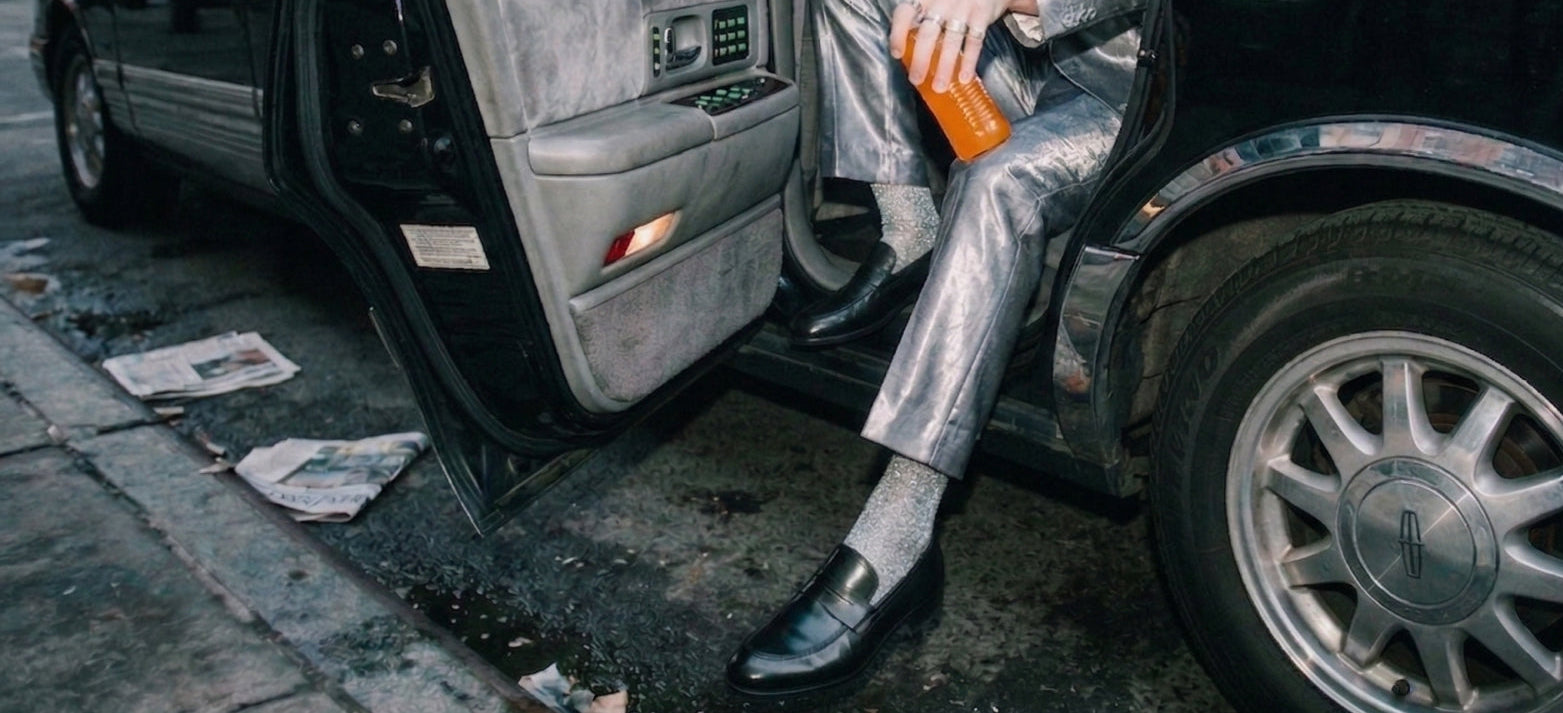 Man stepping out of limo wearing a silver suit and men's Italian black leather loafer dress shoes