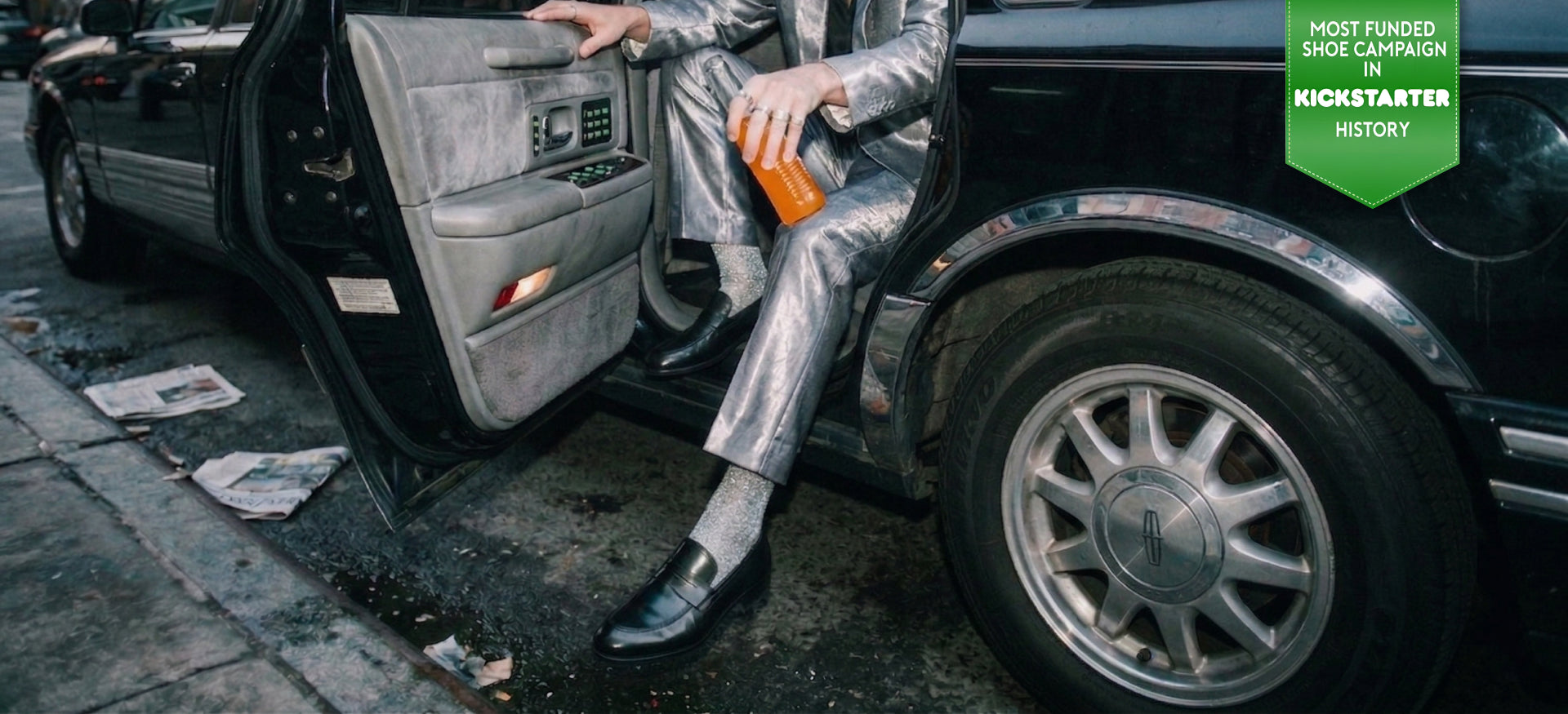 Man stepping out of limo wearing a silver suit and men's Italian black leather loafer dress shoes