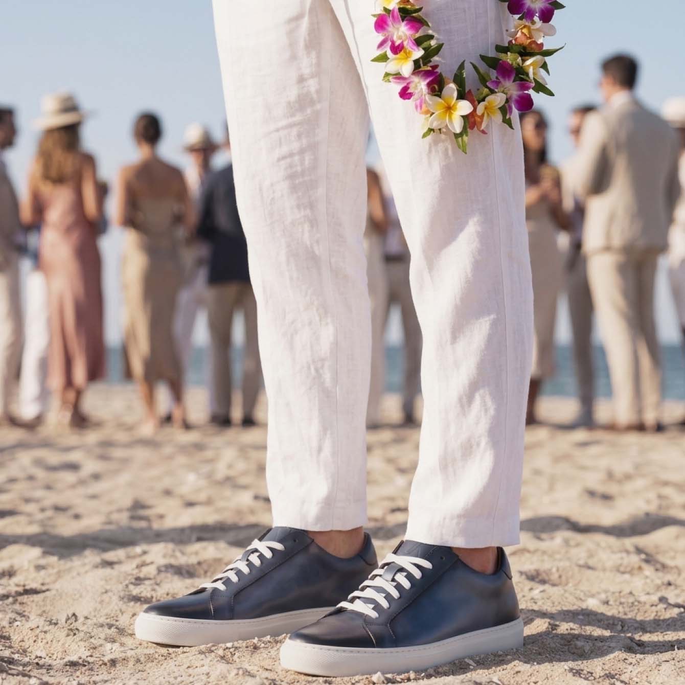Man standing at beach wedding wearing men's Italian blue leather lace-up sneakers with white rubber soles